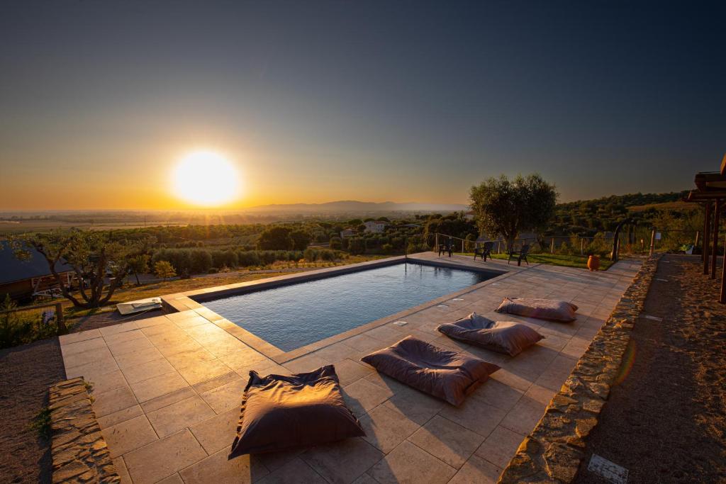 a pool with pillows and the sunset in the background at Glamping Grancia in Grosseto
