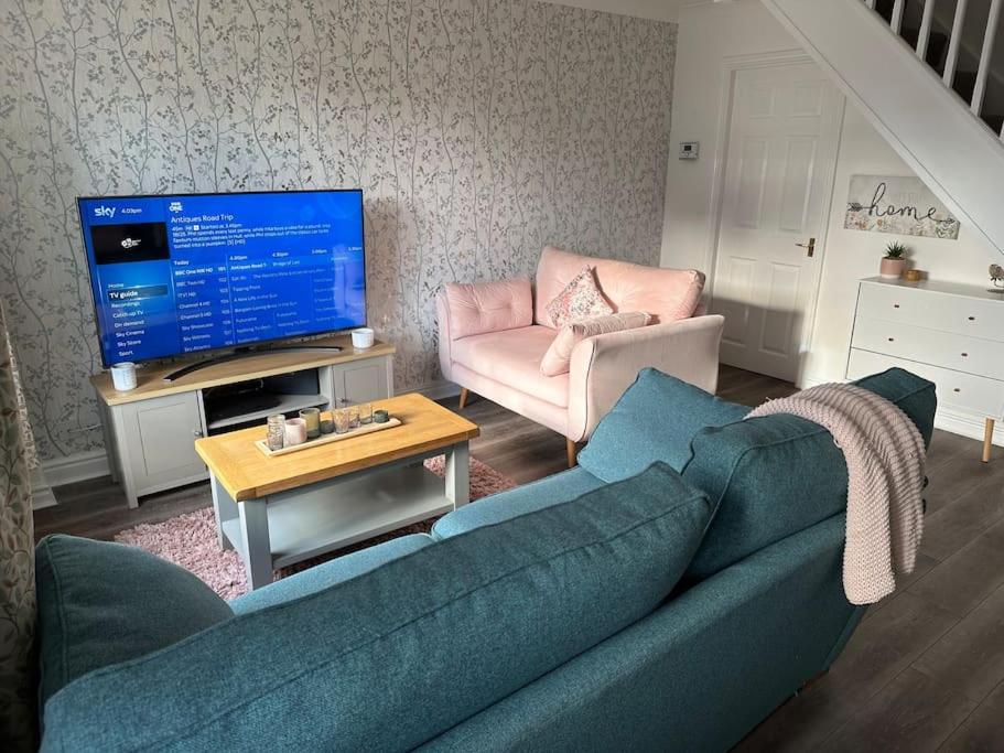 a living room with a blue couch and a television at Cosy home in Warrington in Great Sankey