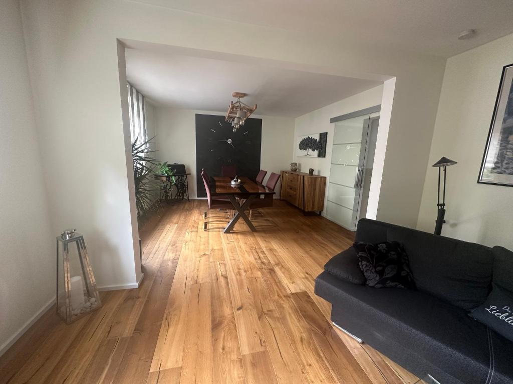 een woonkamer met een zwarte bank en een houten vloer bij Martins Ferienhäusle in Ochsenfurt