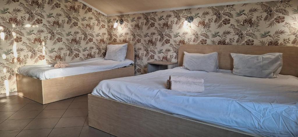 two beds in a room with floral wallpaper at Lisova - Лісова готельня і сауна in Kyiv