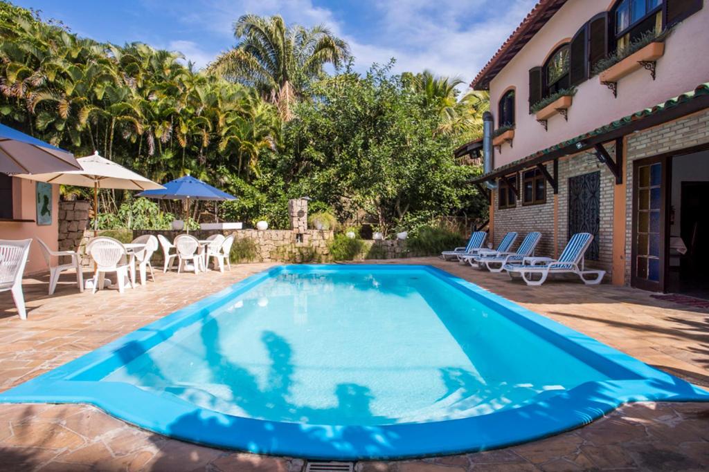 a large blue swimming pool next to a house at Feiticeira Praia Hotel in Ilhabela