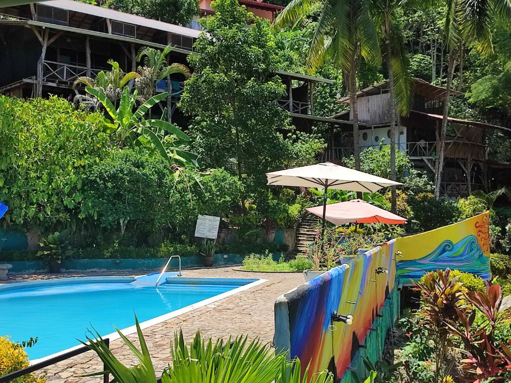 a swimming pool with an umbrella next to a resort at Hostel Plinio in Manuel Antonio