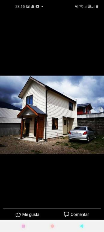 a white house with a car parked in front of it at Cabañas ali in Puerto Aisén