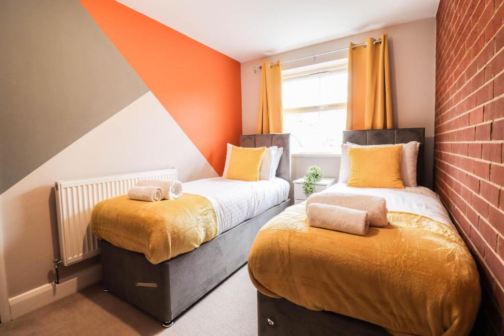 two beds in a small room with orange walls at Family-Friendly 4 Bedroom House with Private Driveway in Hillingdon