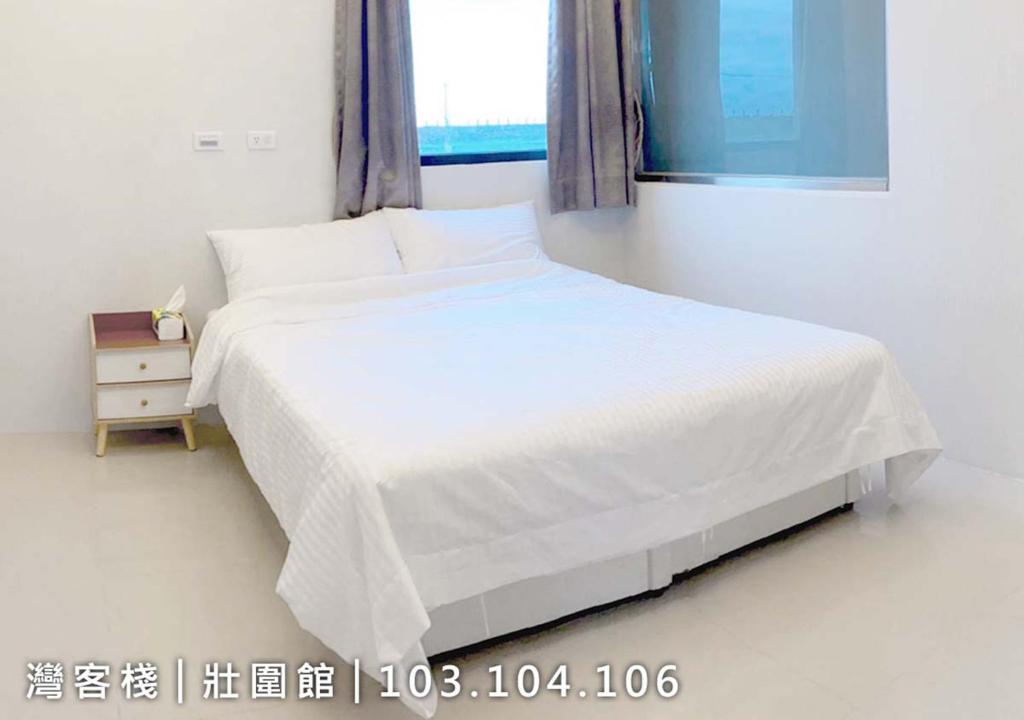 1 dormitorio con cama blanca y ventana en 灣客棧壯圍56館 en Yilan City