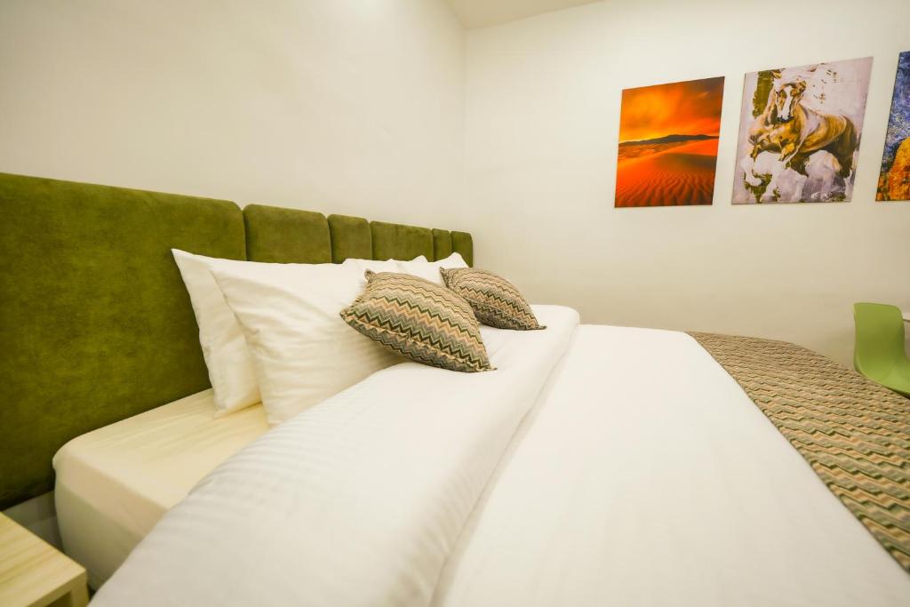 uma cama com lençóis brancos e almofadas num quarto em simple street apartment em Wadi Musa