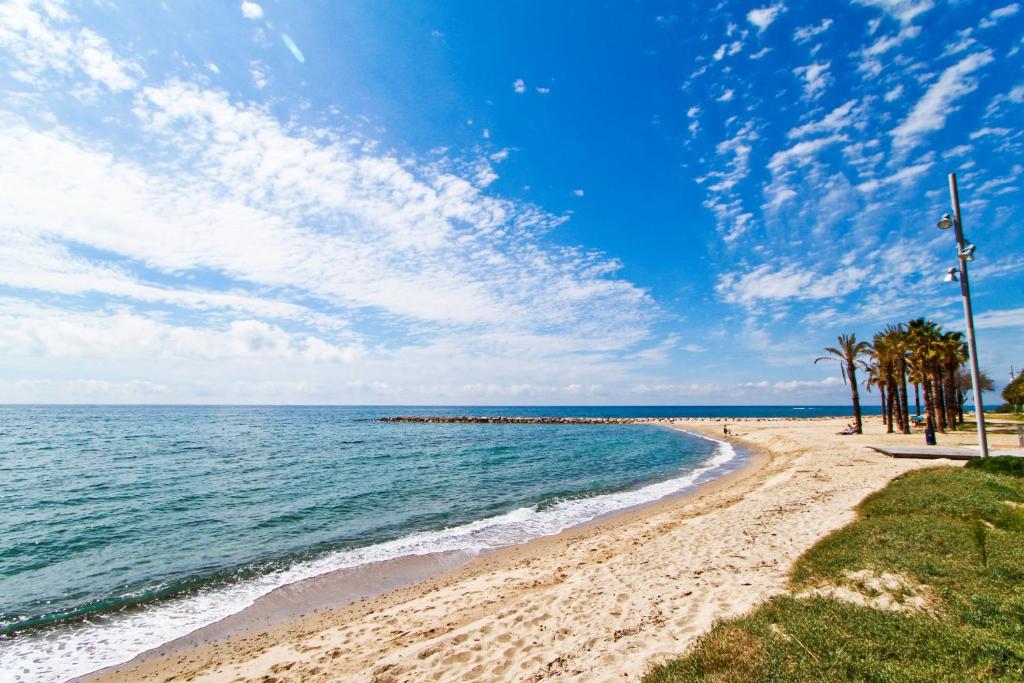 una playa de arena con palmeras y el océano en MAEVA HomeStay by Turismar, en Cambrils