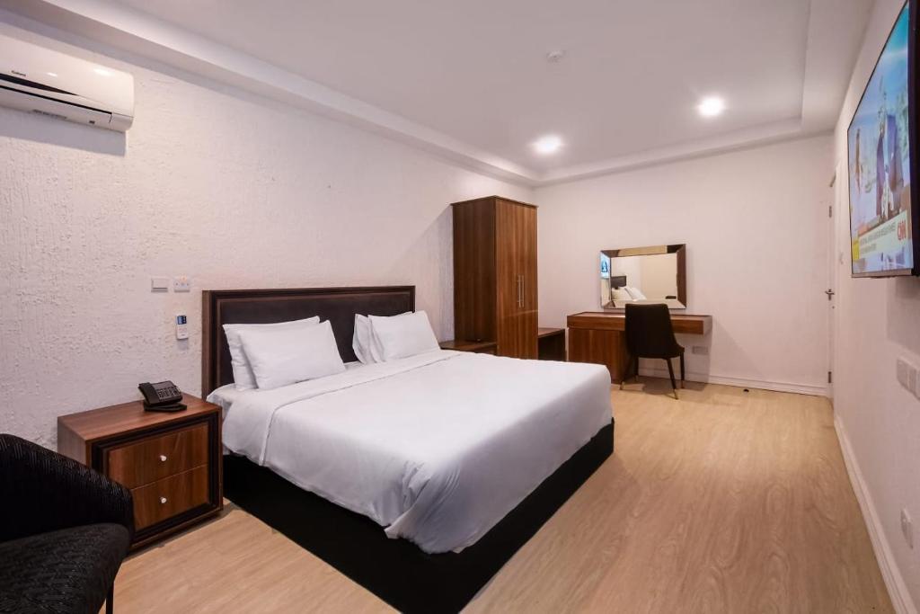 1 dormitorio con 1 cama blanca grande y escritorio en Nicotel Apartments, en Lekki