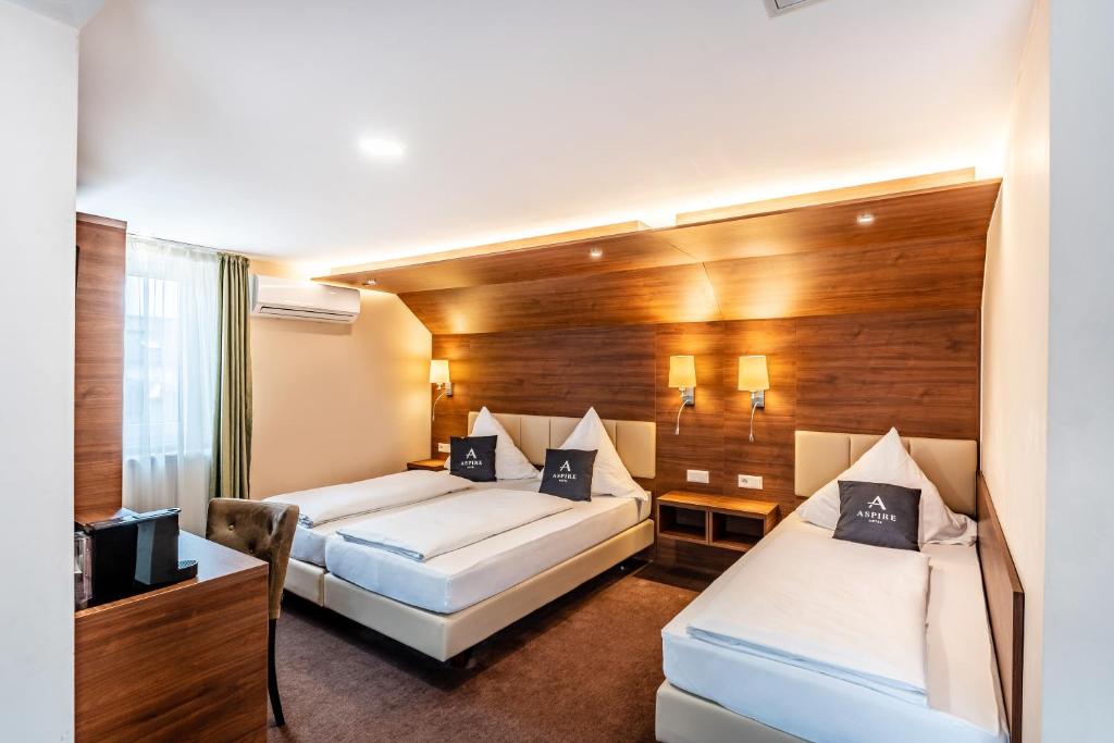 a hotel room with two beds and a desk at Aspire Castillo Reutlingen, Trademark Collection by Wyndham in Reutlingen