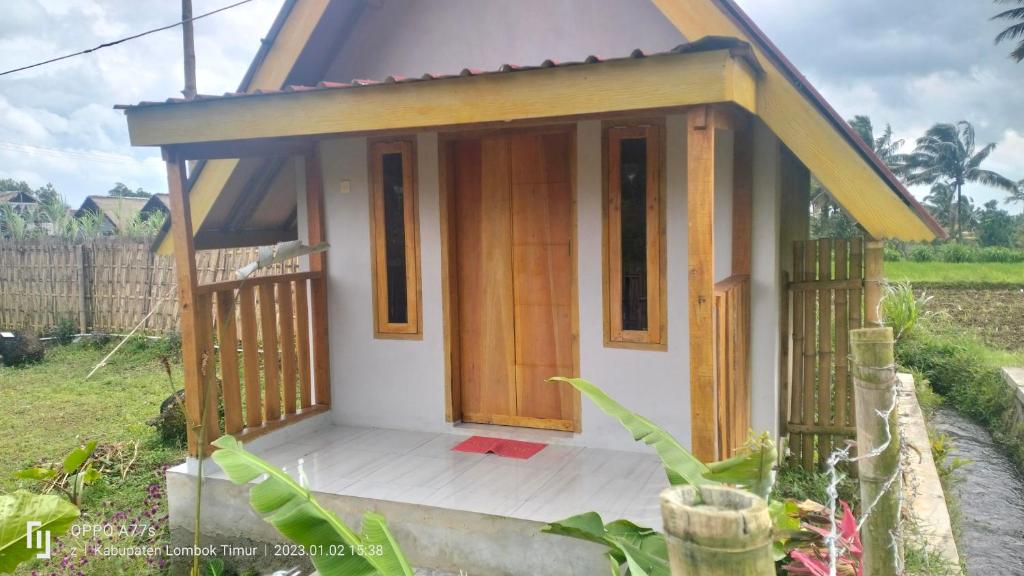 a small house with a door in a yard at Sunset Point Kembang Kuning in Tetebatu