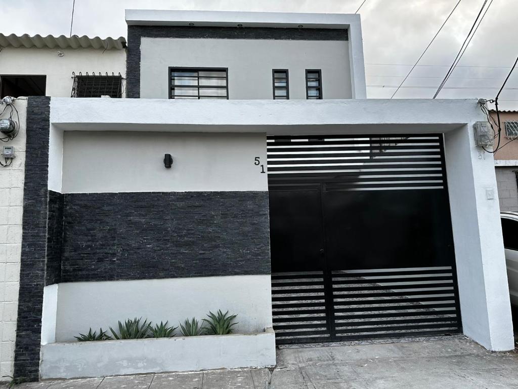 a black and white house with a garage at Merliot, Sta Tecla Frente Cto Comer La Plaza Merliot in Nueva San Salvador