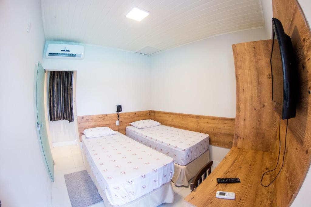 um quarto com 2 camas e uma televisão de ecrã plano em Pousada Veneza em Itabuna