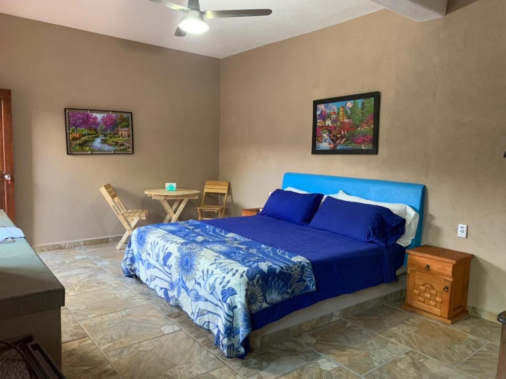 Bungalows Victoria في لا مانزايلا: غرفة نوم بسرير ازرق وطاولة