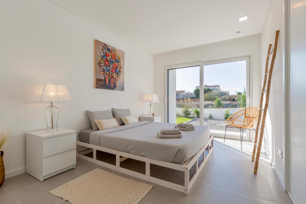 Villa Estrela في لورينها: غرفة نوم بيضاء مع سرير وشرفة