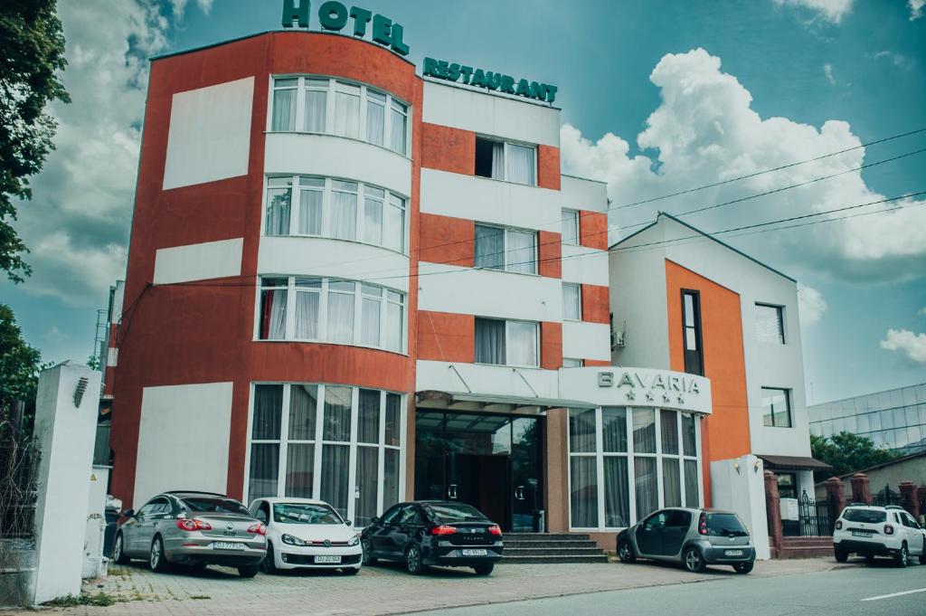 a building with cars parked in front of it at Hotel Bavaria in Craiova
