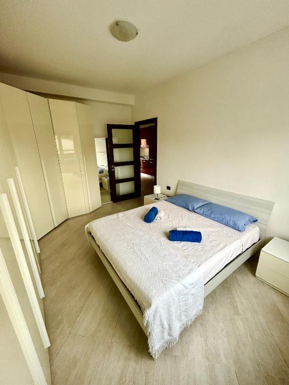 una camera da letto con un grande letto bianco con cuscini blu di Grazioso Bilocale alle Porte di Milano a Paderno Dugnano