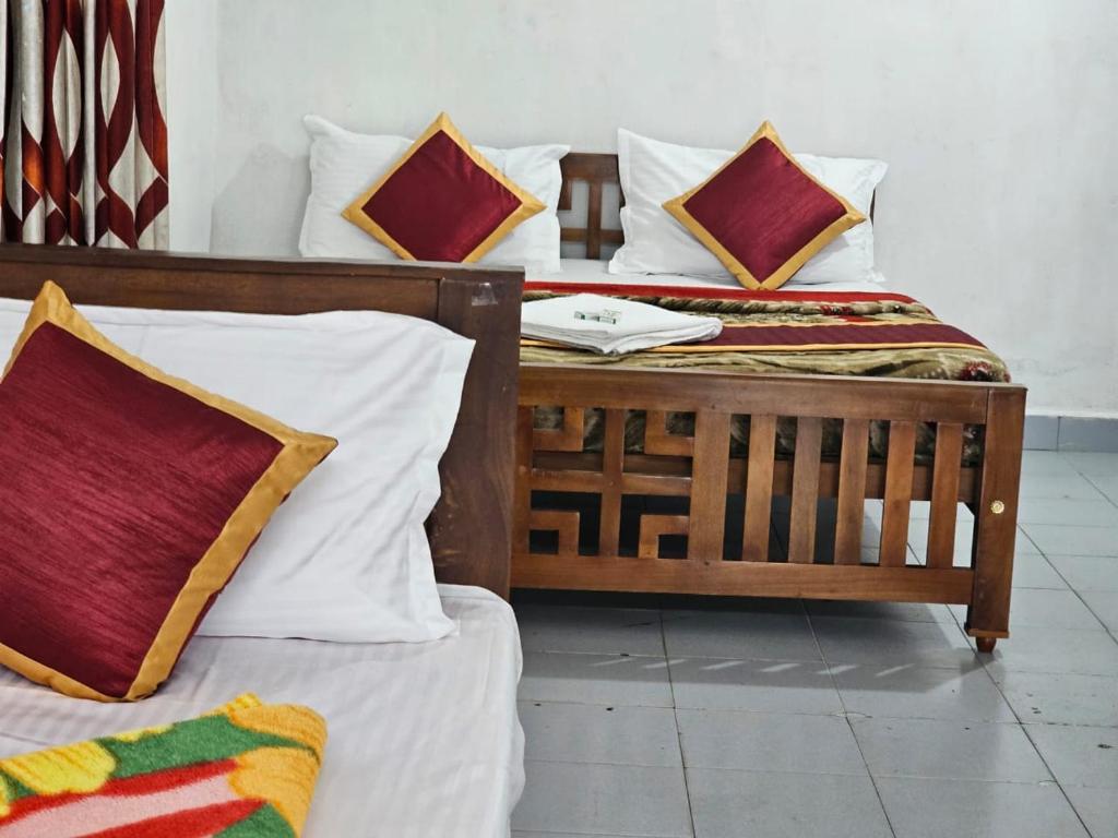 2 camas individuales con almohadas en Cicily Holidays Inn, en Munnar