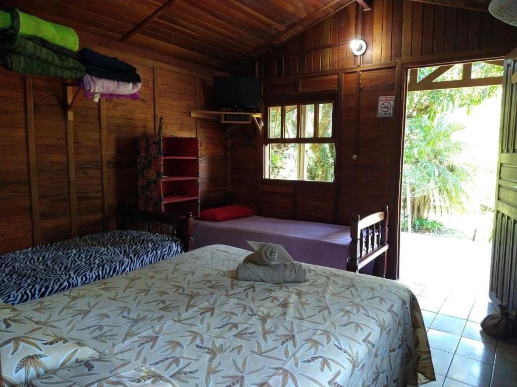 ein Schlafzimmer mit einem Bett in einer Holzhütte in der Unterkunft Pousada do Cowboy in Sapucaí-Mirim