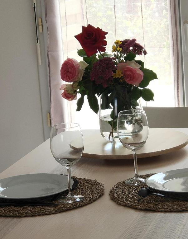 a table with two glasses and a vase of flowers at Tresor de Beaurains in Beaurains