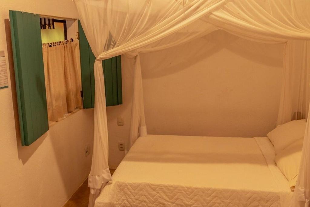 a bedroom with a white bed with a canopy at Suites da Loja Caraíva in Porto Seguro