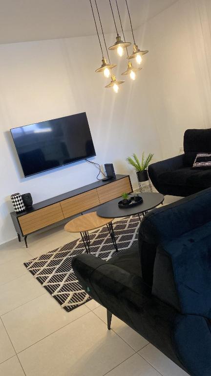 a living room with a flat screen tv and a couch at מצפור הכנרת- דירת גן לאירוח in Tiberias