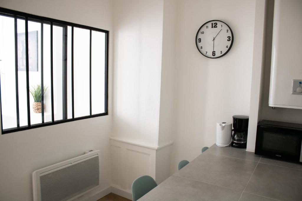 une salle à manger avec une horloge sur le mur et une table dans l'établissement La Galerie de Lumière 201, à Aurillac