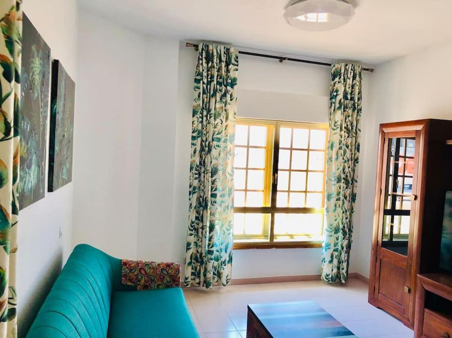 un salon avec un canapé bleu et une fenêtre dans l'établissement Casa playa Las Canteras, à Las Palmas de Gran Canaria
