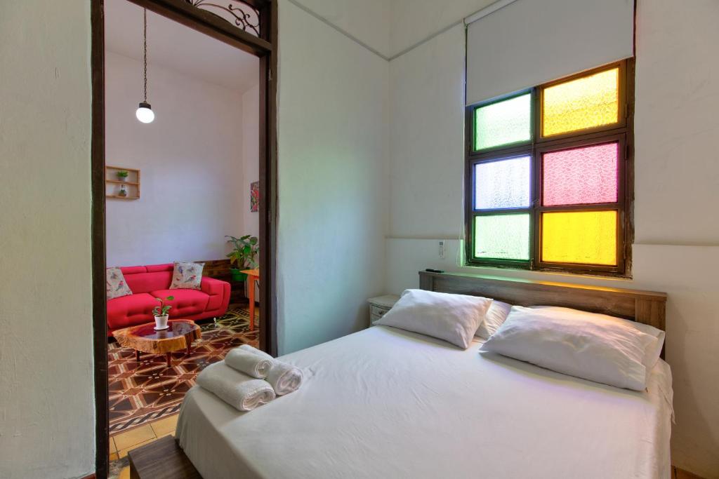 a bedroom with a white bed and a red couch at Casa Blanca San Antonio Hostal Boutique in Cali