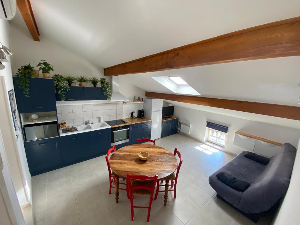 a kitchen with blue cabinets and a wooden table and chairs at Appartement climatisé au pied du Mont Ventoux in Malemort-du-Comtat
