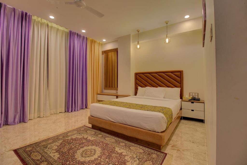 ナーシクにあるGreenstones Boutique Hotelのベッドルーム1室(紫色のカーテンとラグ付きのベッド1台付)
