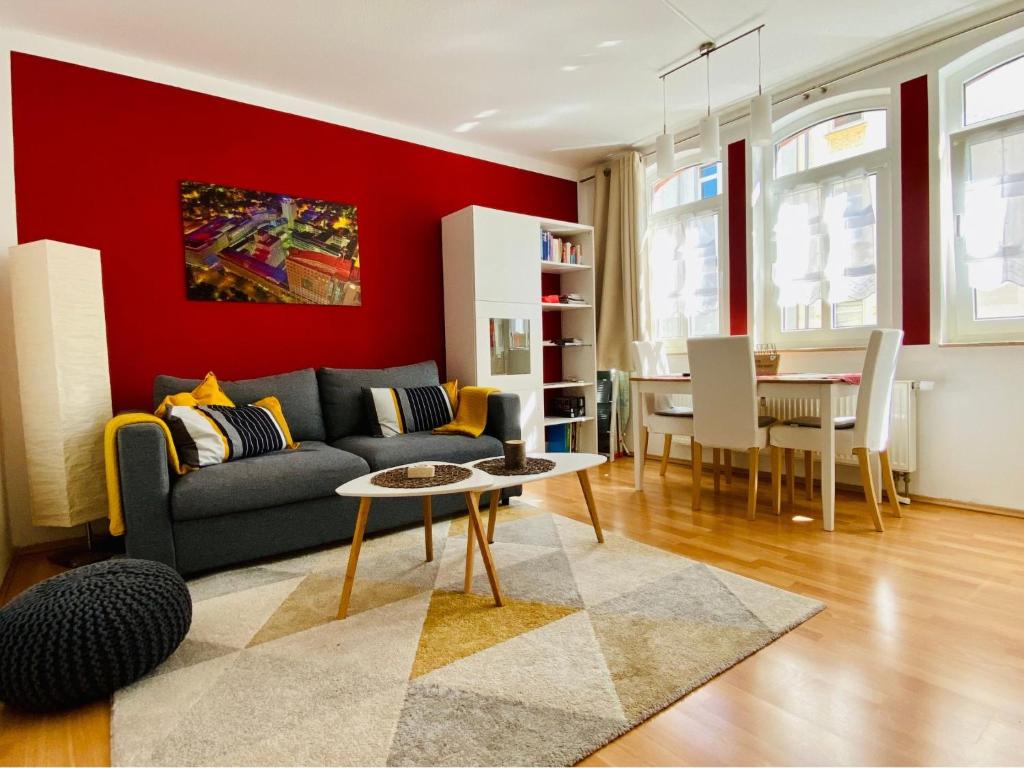 a living room with a couch and a red wall at Zentral & ruhig, ideal für Home Office mit Garten in Jena