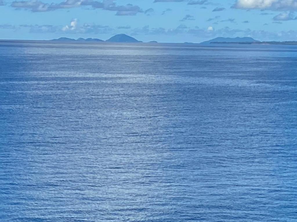 uma grande massa de água com montanhas à distância em Au PETIT NONI em Le Gosier