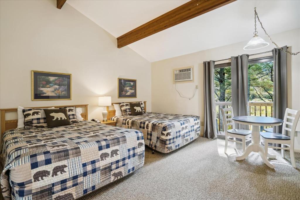 sypialnia z 2 łóżkami, stołem i krzesłami w obiekcie Cedarbrook Deluxe Two Bedroom Suite with outdoor heated pool 20304 w mieście Killington