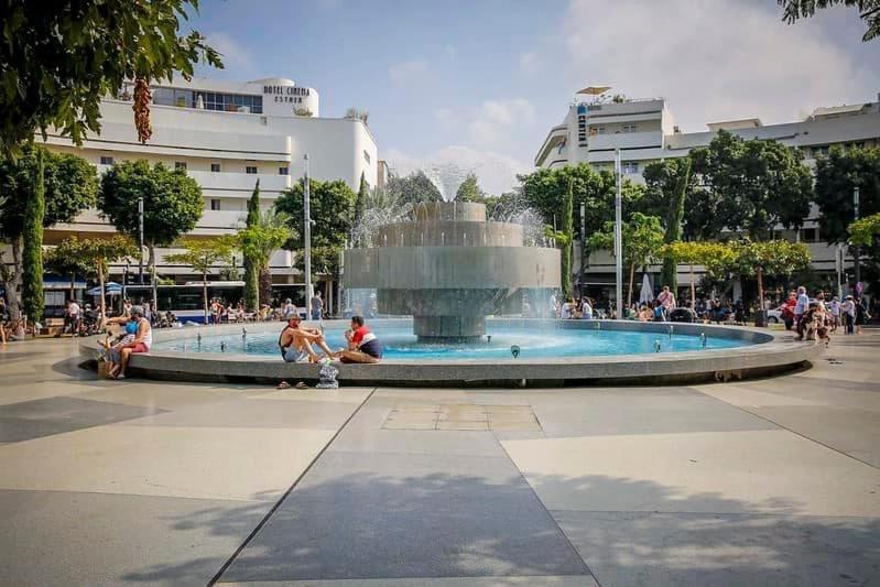 une fontaine dans une ville avec des gens assis autour de celle-ci dans l'établissement Beautiful apartment - Dizengoff square, à Tel Aviv