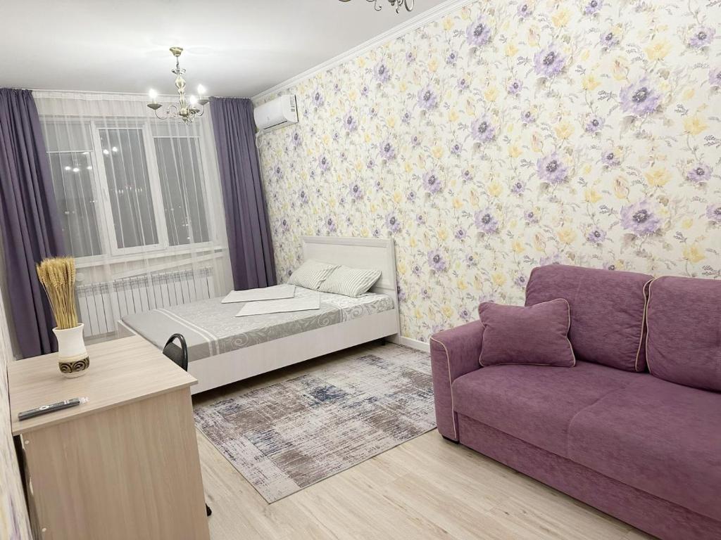 sala de estar con sofá púrpura y cama en Апартаменты в ЖК Аманат, en Almaty