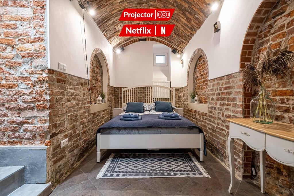 um quarto com uma cama numa parede de tijolos em Old Town WAWEL II Premium Apartment – 52m2 em Cracóvia
