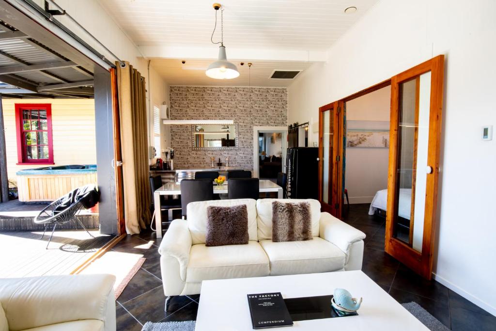 a living room with two white couches and a kitchen at The Factory Luxury Accomodation in Kaikoura