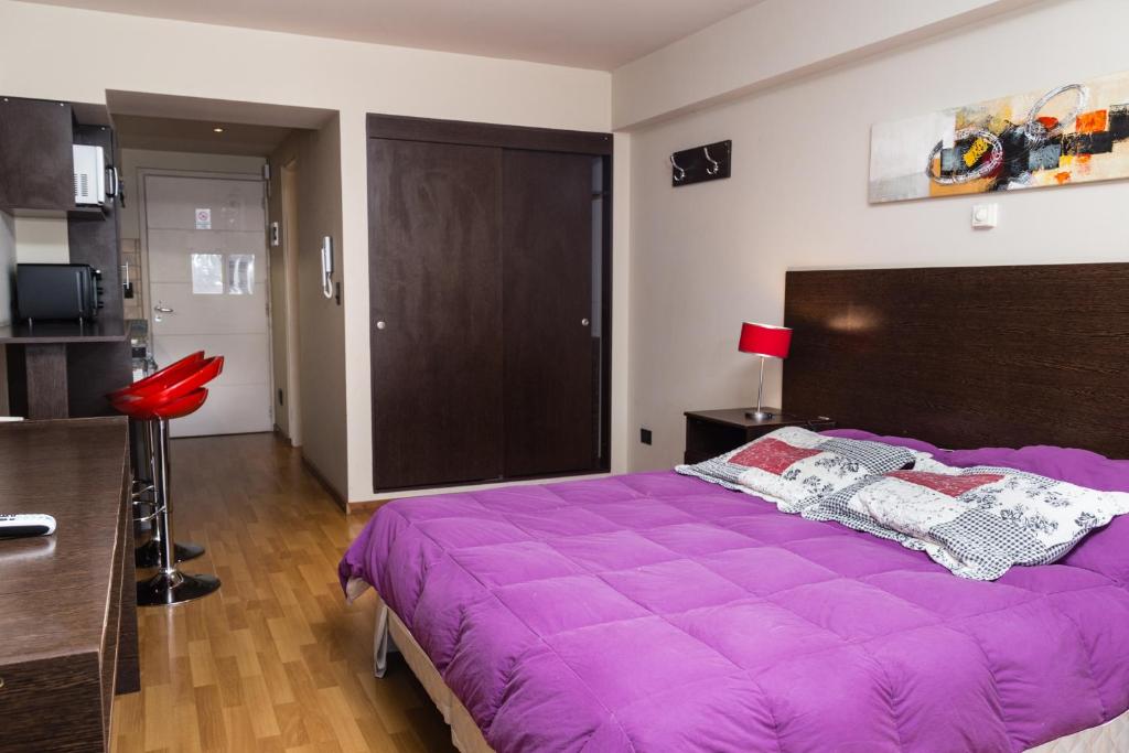 ein großes lila Bett in einem Zimmer mit Küche in der Unterkunft Alojamientos Bariloche in San Carlos de Bariloche