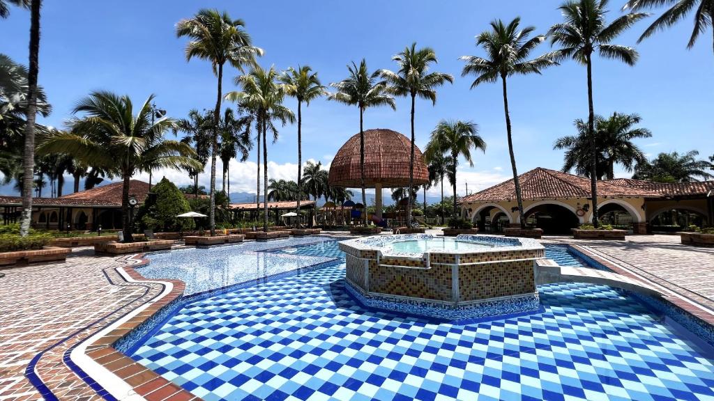 uma piscina de resort com palmeiras ao fundo em Tequendama Hotel Campestre Villavicencio em Villavicencio