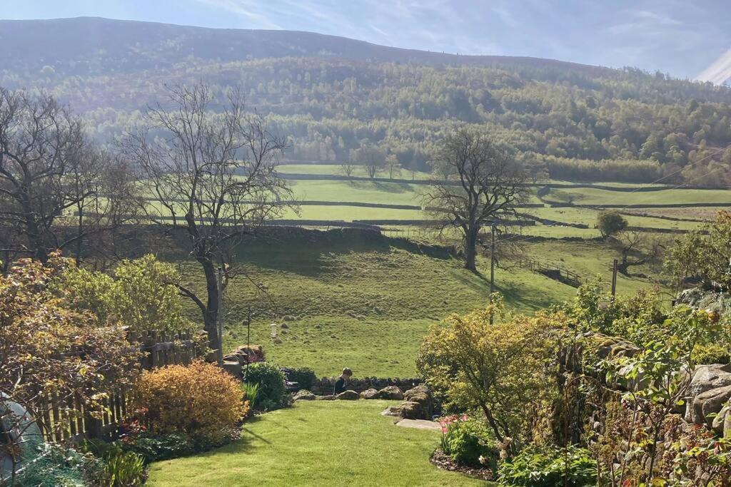 a view of a green field with trees and hills at Stunning 3 bed Yorkshire Dales cottage in Appletreewick