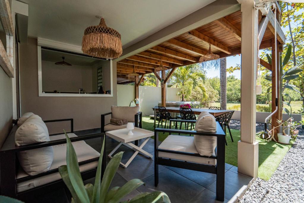 un patio con mesa y sillas bajo una pérgola en La Petite Caravelle Guadeloupe, en Sainte-Anne