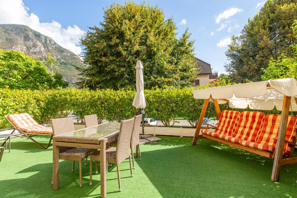 un patio avec un parasol, une table et des chaises dans l'établissement Maison Bruno, à Annecy