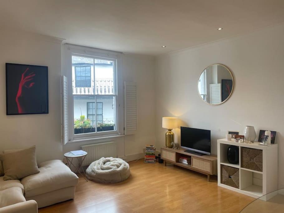a living room with a couch and a television at Spacious 1-bedroom apartment in Belsize Village in London