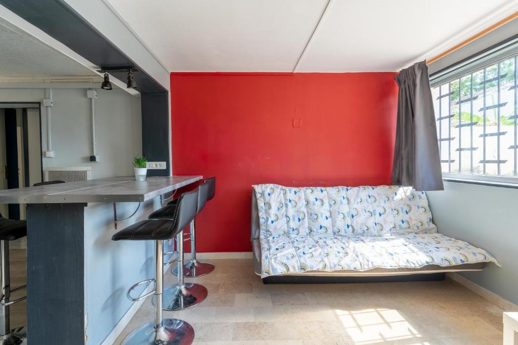 a living room with a couch against a red wall at Maison des Charmettes in Nîmes