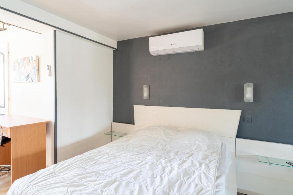a bedroom with a white bed and a gray wall at Maison des Charmettes in Nîmes