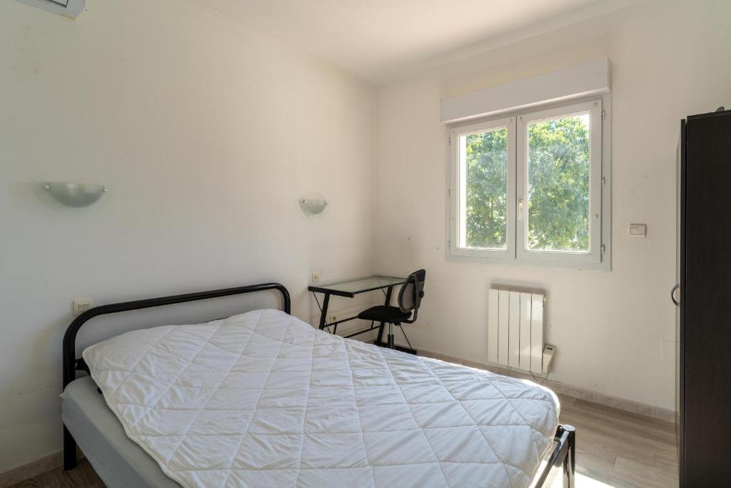 a white bedroom with a bed and a window at Maison des Charmettes in Nîmes
