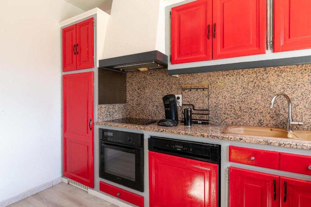 a kitchen with red cabinets and a sink at Maison des Charmettes in Nîmes
