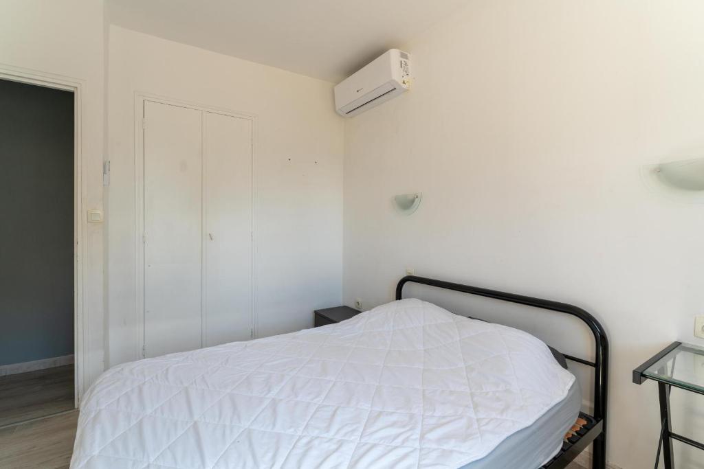 a bedroom with a white bed and a white wall at Maison des Charmettes in Nîmes