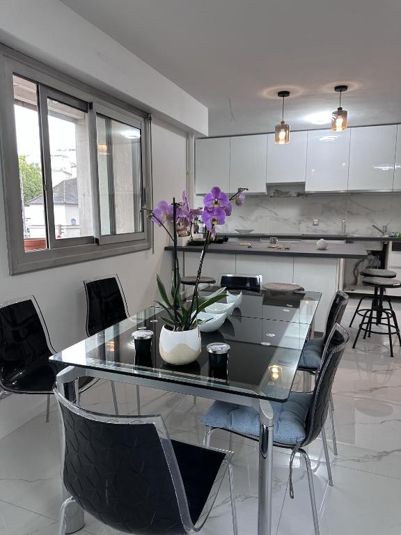 une salle à manger avec une table en verre avec des fleurs violettes dessus dans l'établissement Paris expo Cosy appt T5 avec Jardin, à Paris