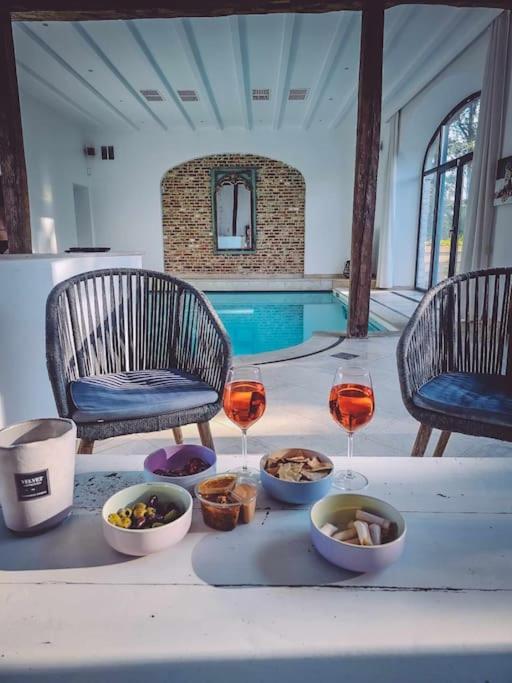a table with food and wine glasses and a swimming pool at Gîte de l'Ourchet in Ramillies